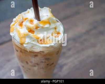 Close-up Iced caramello macchiato marrone con paglia nel bicchiere. Il freddo bevanda caffè frappé (frappuccino con panna e sciroppo di caramello e br Foto Stock