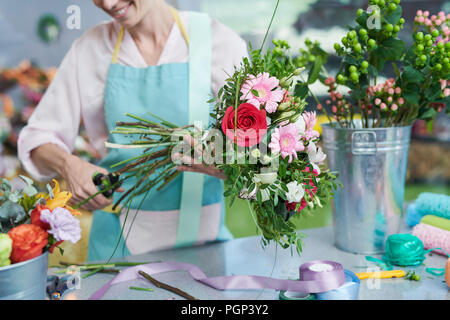 Vista del raccolto di sorridere un fioraio intestatura steli di fiori Foto Stock