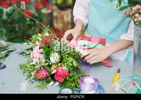 Primo piano di un irriconoscibile fioraio legatura di bella rosa boquet Foto Stock