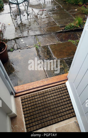 Aprire lo sportello di un cottage porta a vedere la pioggia sul patio in pietra lastre in Sheffield, Yorkshire, Inghilterra. Foto Stock