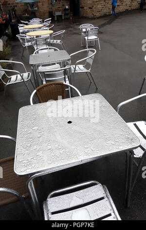 L'acqua piovana globuli di acqua a depositare su cafe tavole metalliche a Yorkshire Centro di antiquariato, Inghilterra Foto Stock