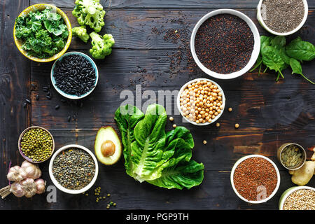 Materie semi, cereali, fagioli, superfoods e verdura verde scuro sul tavolo di legno vista dall'alto. vegetariana o dieta concetto alimentare Foto Stock