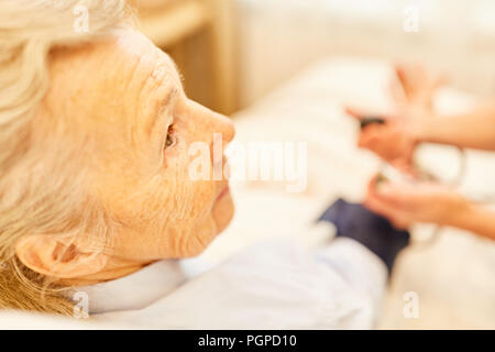 Senior della donna come un paziente tenendo la pressione del sangue nel campo dell'assistenza infermieristica presso la casa di cura Foto Stock