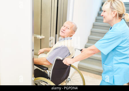 Il caregiver spinge senior uomo in sedia a rotelle nel campo dell'assistenza infermieristica presso la casa di riposo Foto Stock