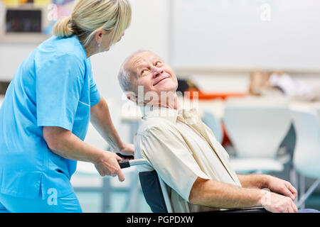 Demented senior in sedia a rotelle viene curato da un infermiere in Cura geriatrica Foto Stock