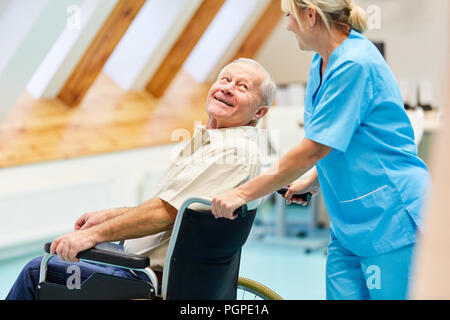 Un infermiere si prende cura di senior uomo in sedia a rotelle in assistenza agli anziani Foto Stock