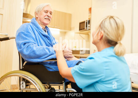 Il caregiver si prende cura preoccuparsi di senior uomo in sedia a rotelle in assistenza agli anziani Foto Stock