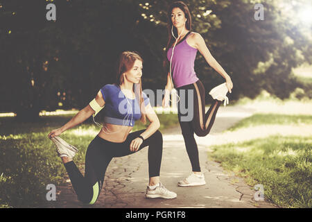 Due giovani e montare le ragazze stretching prima di fare jogging nel parco su una mattina di sole (effetto vintage) Foto Stock