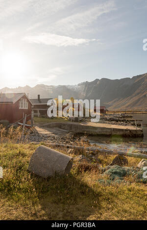 Fasci di luce con lens flare su un picco di montagna shining giù sopra una capanna sulla spiaggia in Tromso, Norvegia in una nebbiosa giornata in una scenografica landsc rurale Foto Stock