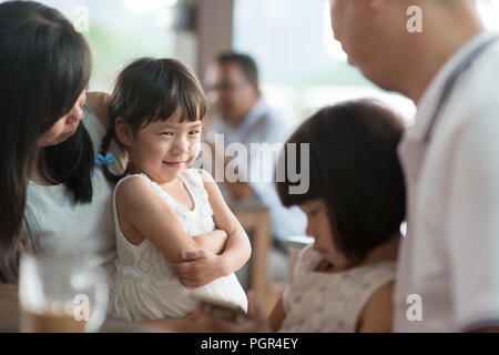 Candide sparare delle persone nella caffetteria. Bambina con vari faccia espressione. Famiglia asiatica outdoor lifestyle con luce naturale. Foto Stock