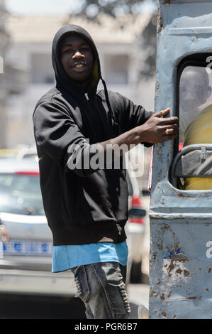 SAINT LOUIS, SENEGAL - Apr 24, 2017: Non identificato uomo senegalese si erge sul retro scala di bus nel centro di Saint Louis, uno dei principali ci Foto Stock