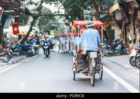 Cyclo tradizionale corsa giù per le strade di Hanoi, Vietnam. Il cyclo è un tre ruote taxi bicicletta che è comparso in Vietnam in francese coloniale. Foto Stock