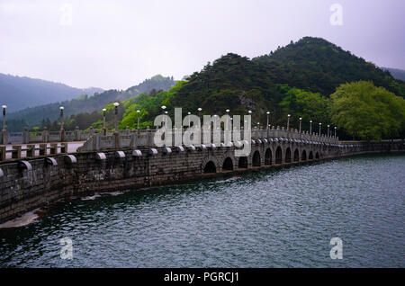 Ponte cinese su una diga con Lulin lago e montagne verdi vista nel Parco nazionale di Lushan nello Jiangxi Cina Foto Stock