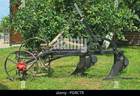 Vecchio vintage restaurati seduta dell'aratro sull'erba in cantiere Foto Stock