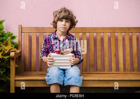 Little Boy holding pila di libri con leggere apple e matite pronti per tornare a scuola. Foto Stock