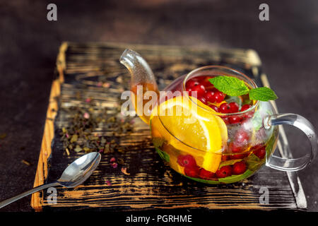 Teiera con calda tè di frutta su sfondo scuro Foto Stock