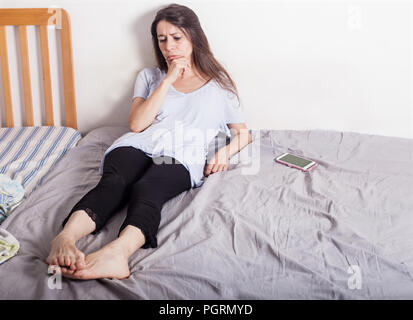 Turbato la donna di stare nella sua camera da letto al giorno, triste e preoccupato Foto Stock