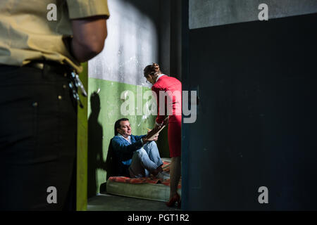 Femmina dedicato attorney visitando un giovane detenuto in un obsoleto cella di prigione Foto Stock