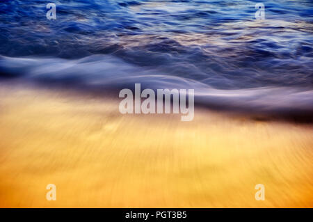 Blu e Oro setosa onde che si infrangono sulla riva con riflessione al tramonto lungo la spiaggia a piedi nudi, Florida Foto Stock