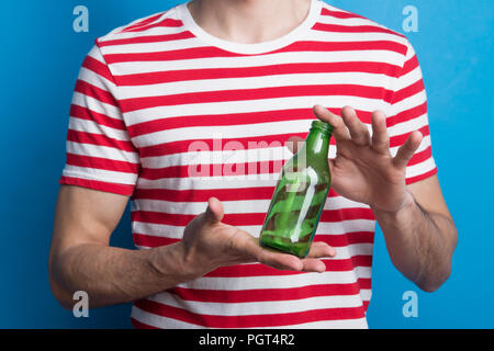 Un close-up di un irriconoscibile uomo in uno studio di trattenimento di un flacone vuoto nelle sue mani. Foto Stock