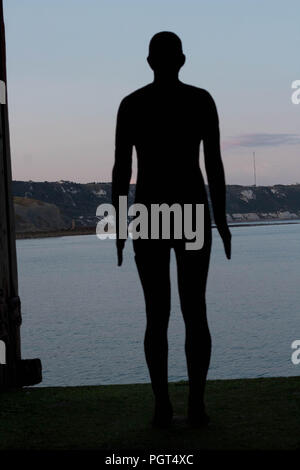 Viaggi & Turismo - illustrazione schematica di uno di Anthony Gormley's Folkestone cast triennale di scultura in piedi vicino al bordo del porto, Folkestone, Kent, Regno Unito Foto Stock