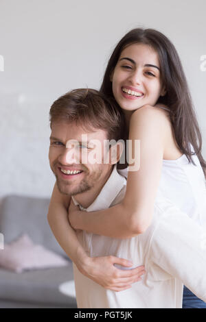 Felice giovane ragazza sorridente piggyback fidanzato divertendosi al Foto Stock