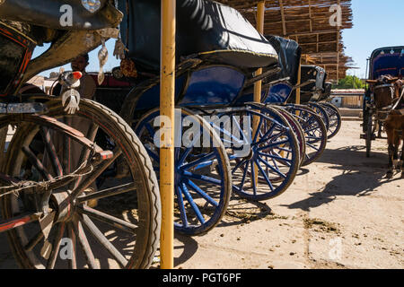 Colorato di trasporto turistico carrozze parcheggiata sotto la tenda di paglia in ombra,Tempio di Edfu, Egitto, Africa Foto Stock