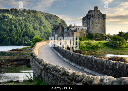 Luce della Sera il restaurato castello Eilean Donan sull isola a tre laghi con aggiunta di arco in pietra passerella Highlands scozzesi Scotland Regno Unito Foto Stock