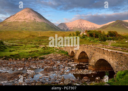 Sligachan vecchio ponte di pietra sul fiume Sligachan con Glamaig e Beinn Dearg Mhor picchi di Red Cuillin montagne al tramonto Isola di Skye in Scozia UK Foto Stock