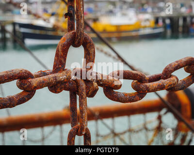 Metallo arrugginito catene delle reti da pesca di un peschereccio barca ormeggiata nel porto di Newlyn. In Newlyn, Cornwall, Inghilterra. Foto Stock