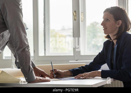 Due architetti per discutere il documento a una scrivania in ufficio. Foto Stock
