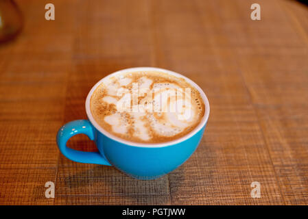 Blu tazza di caffè sul tavolo di legno oltre il moderno Cafe' iterior. Foto Stock