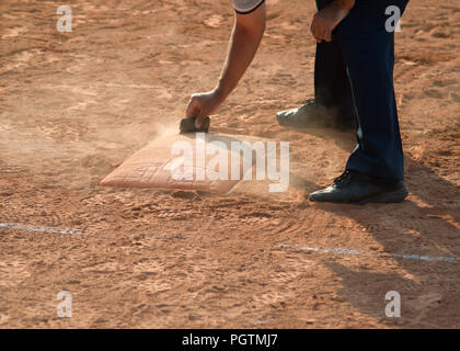 Arbitro pulisce home piastra in un baseball (softball) campo polveroso, con copyspace Foto Stock