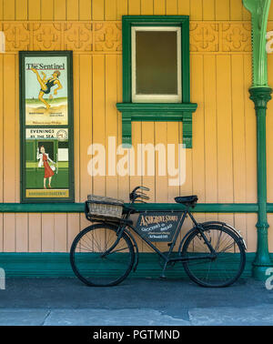 Bicicletta verde con pannello pubblicitario appoggiato contro una parete su una piattaforma a Horsted Keynes patrimonio stazione ferroviaria, East Sussex, Inghilterra Foto Stock