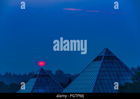 Sole sorge attraverso il fumo riempita sky, Muttart Conservatory Piramidi di Edmonton, Alberta, Canada. Foto Stock