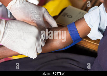 Un lavoratore di salute di assunzione di un campione di sangue dalla vena cubital forando la vena e la raccolta di sangue in una provetta di test sotto pressione negativa Foto Stock