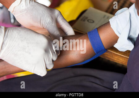 Un lavoratore di salute di assunzione di un campione di sangue dalla vena cubital forando la vena e la raccolta di sangue in una provetta di test sotto pressione negativa Foto Stock