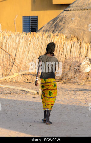 Deserto FERLO, SENEGAL - Apr 25, 2017: Unidentified Fulani ragazza cammina lungo il cantiere da dietro. Fulanis (Peul) sono la tribù più grande in Africa occidentale Foto Stock