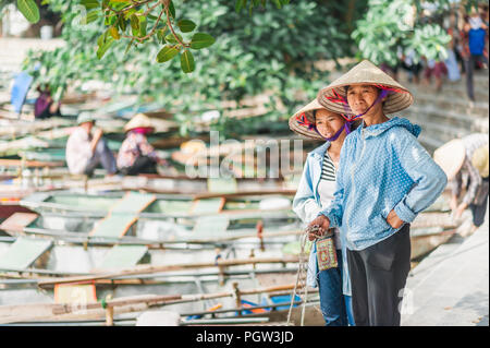 Ottobre 17, 2016 - Van Lam Village, Vietnam. Donna locale in un cappello di riso a guardare oltre le barche a Vung Tram Pier. Pala tradizionale-barche. Foto Stock