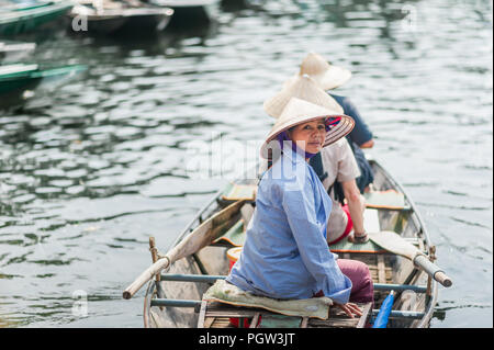 Ottobre 17, 2016 - Van Lam Village, Vietnam. Donna locale in un riso hat remare una barca lontano dalla Vung Tram Pier. Pala tradizionale-barche lungo il Foto Stock