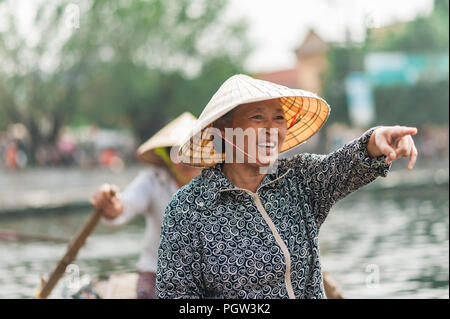 Ottobre 17, 2016 - Van Lam Village, Vietnam. Donna locale in un riso hat remare una barca lontano dalla Vung Tram Pier. Pala tradizionale-barche lungo il Foto Stock