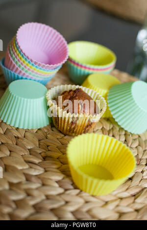 Colorati stampi in silicone per la cottura in forno di tortine e muffin su una cannuccia tabella MAT. Foto Stock