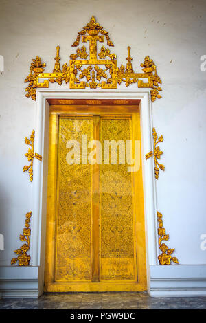 Beautiful golden doppie porte con il bianco muro intonacato sfondo nel tempio thailandese. Foto Stock