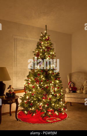 Albero di natale con luci bianche e lampadine rosso in salotto Foto Stock