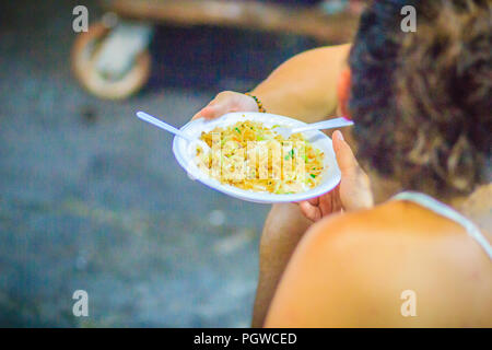 Unidentified tourist comprare e mangiare Pad Thai noodles fritti da street food vendor a Khao San Road mercato notturno, Bangkok, Thailandia. Foto Stock