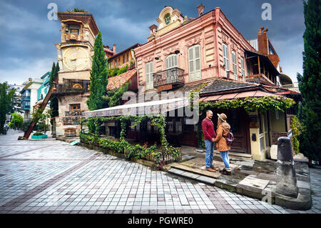 Donna turistiche in marrone cappello e Uomo in camicia rossa cercando su Torre del museo dei burattini in via della centrale di Tbilisi, Georgia Foto Stock