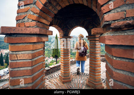 Tourist woman in hat e zainetto a piedi nella chiesa in autunno tempo di nebbia in Signagi, Georgia Foto Stock