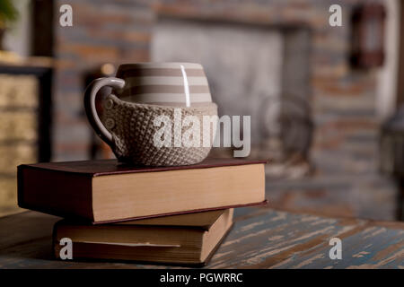 Libri antichi e la tazza di caffè in legno tabella grunge su camino background.Composition con la pila di libri e la tazza di caffè, thè, cacao,copia spazio.tonica image.inverno mattina concetto. Foto Stock