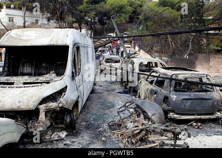 Le persone si mettono in mezzo ai resti carbonizzati della bruciate le vetture in mati est di Atene, Twin di incendi che imperversa nella famosa località zone vicino il greco ca Foto Stock