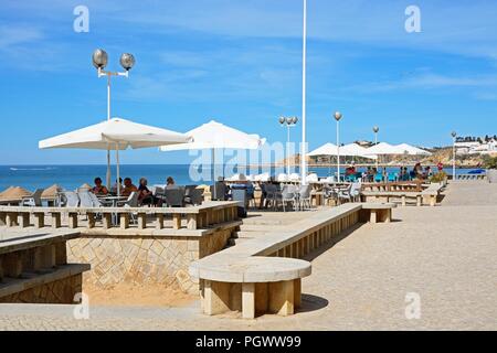 I turisti in un momento di relax a un cafe' sul marciapiede che si affaccia sul mare, Albufeira, Portogallo, Europa. Foto Stock